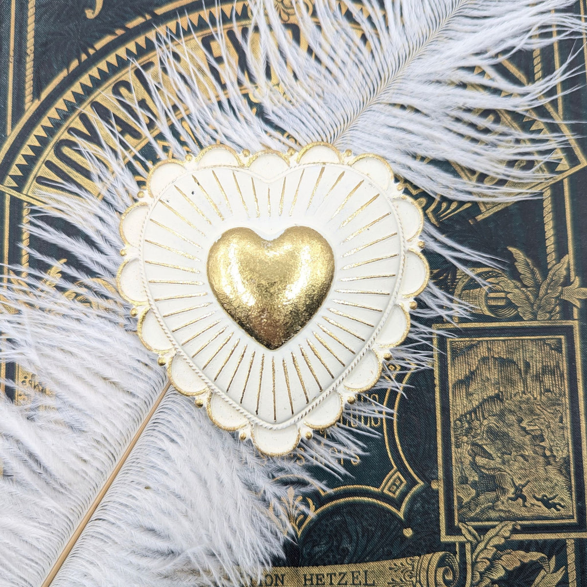 Cœur rayonnant blanc et doré posé sur un livre ancien avec plume blanche