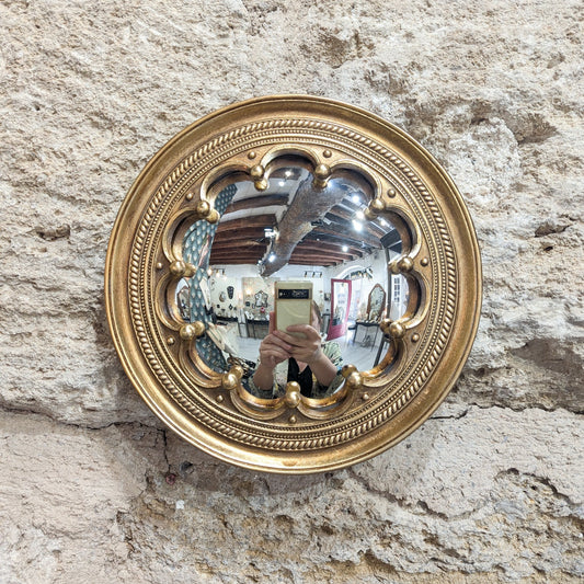 Miroir convexe couronne dorée, miroir de sorcière accroché sur un mur en pierre