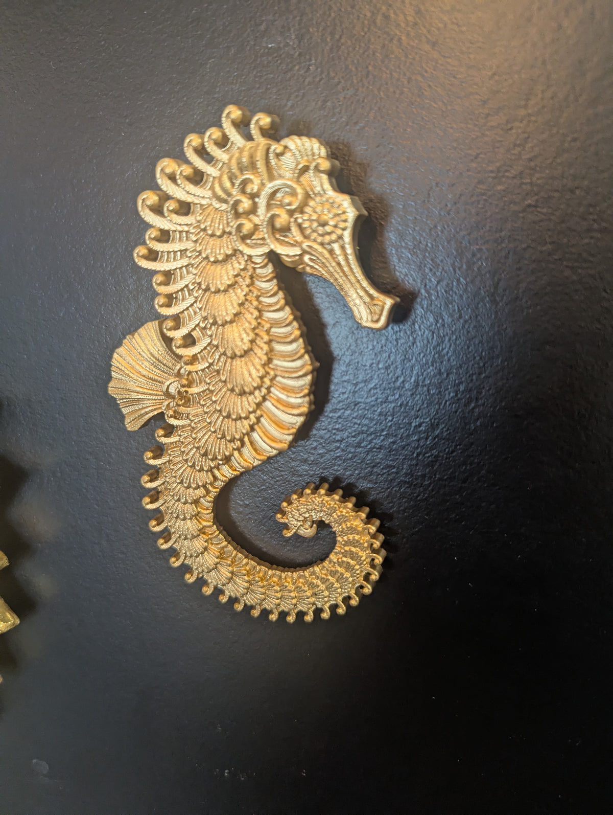 Détail de l'hippocampe doré sur mur sombre, décoration marine