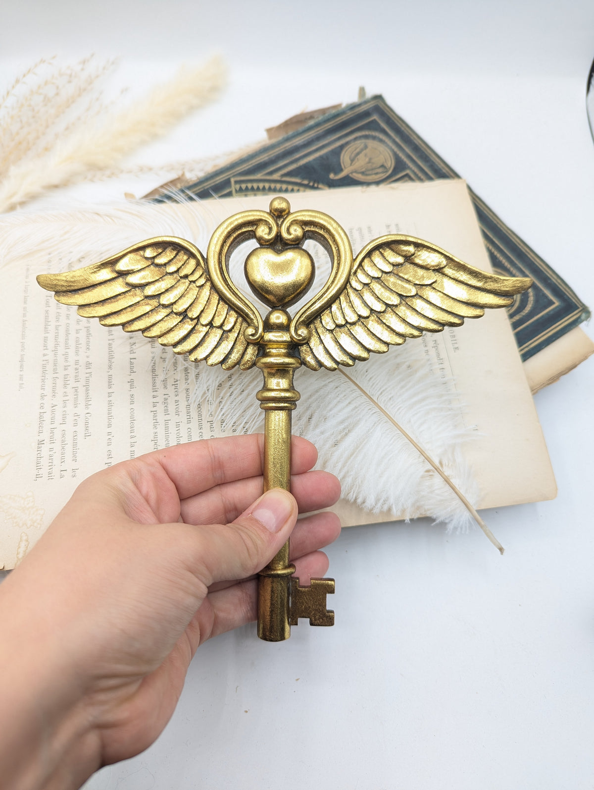 Clé dorée conte de fée à ailes d'ange tenue en main