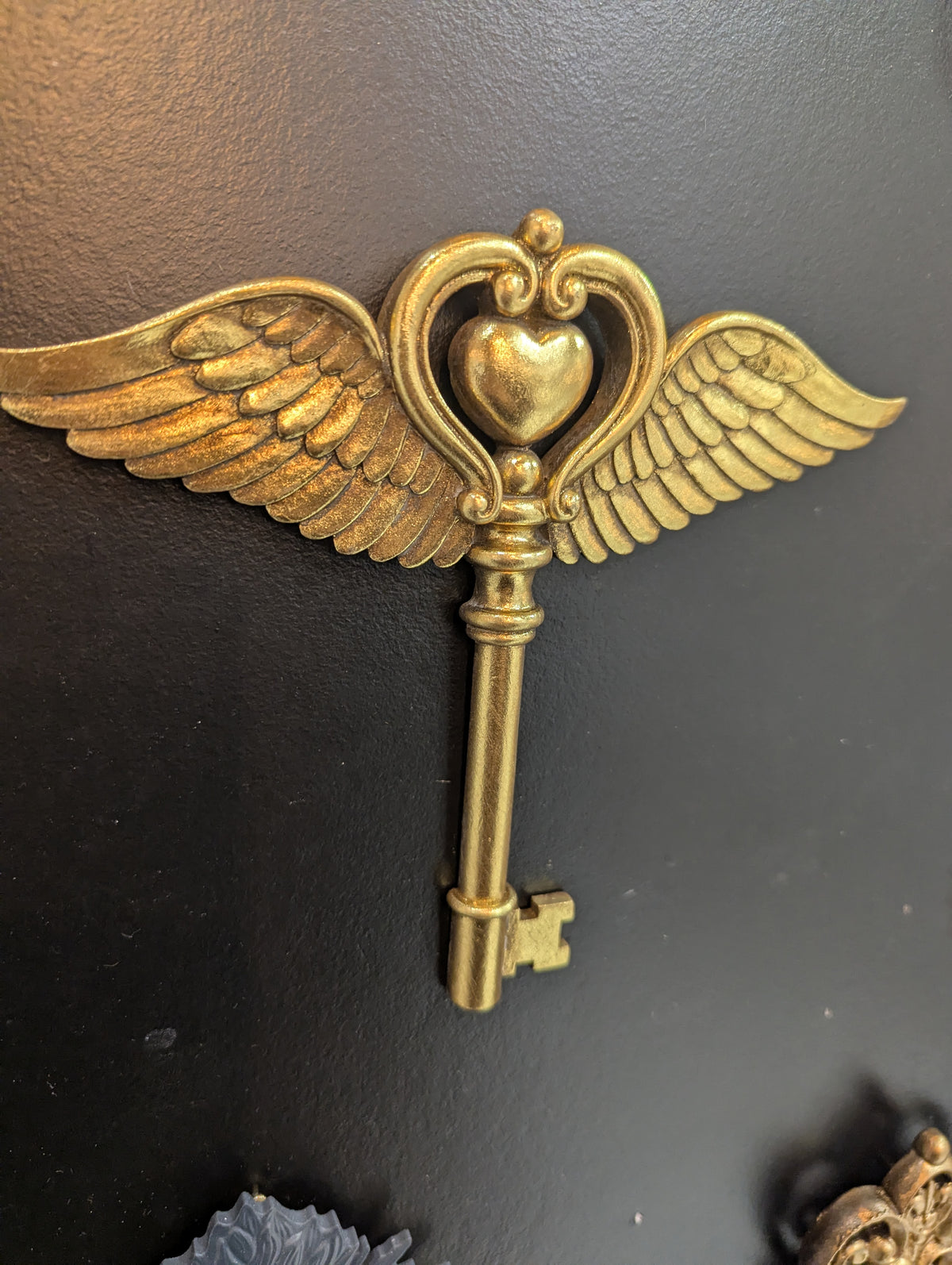 Détail des ailes d'ange et du cœur de la clé dorée