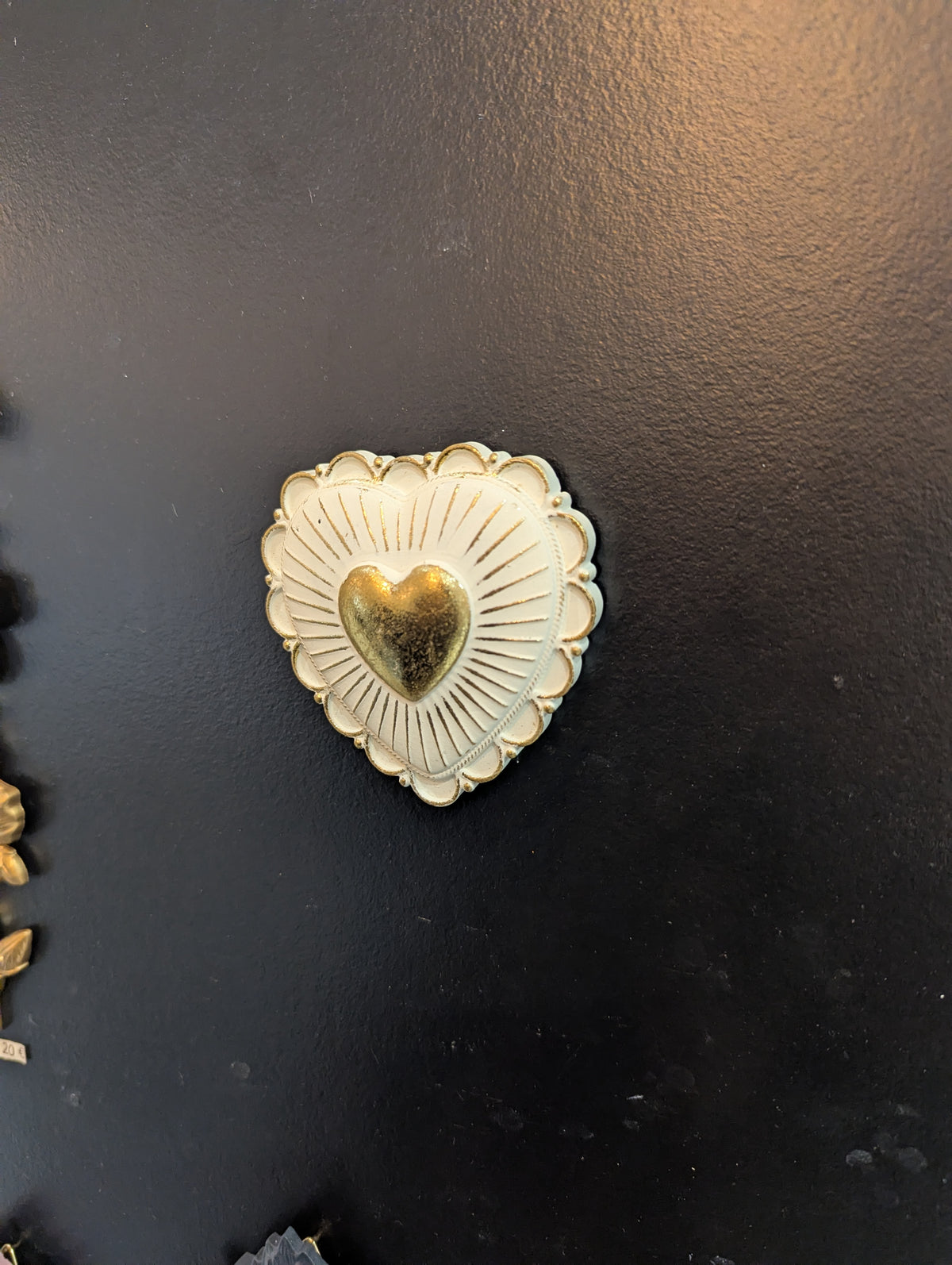 Cœur blanc et doré accroché sur un mur noir