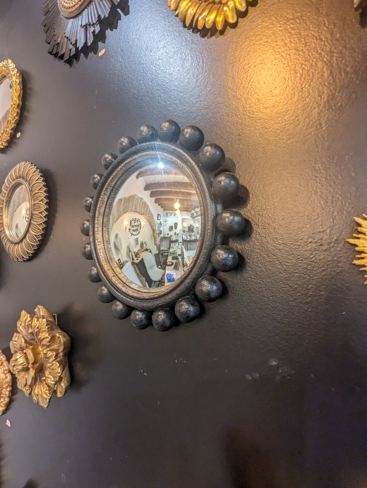 Miroir boule Renaissance noir en composition murale cabinet de curiosité avec décorations dorées