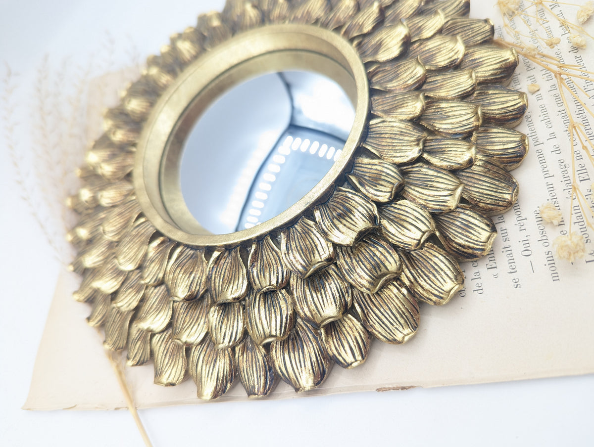 Détail des pétales texturés dorés autour du miroir convexe