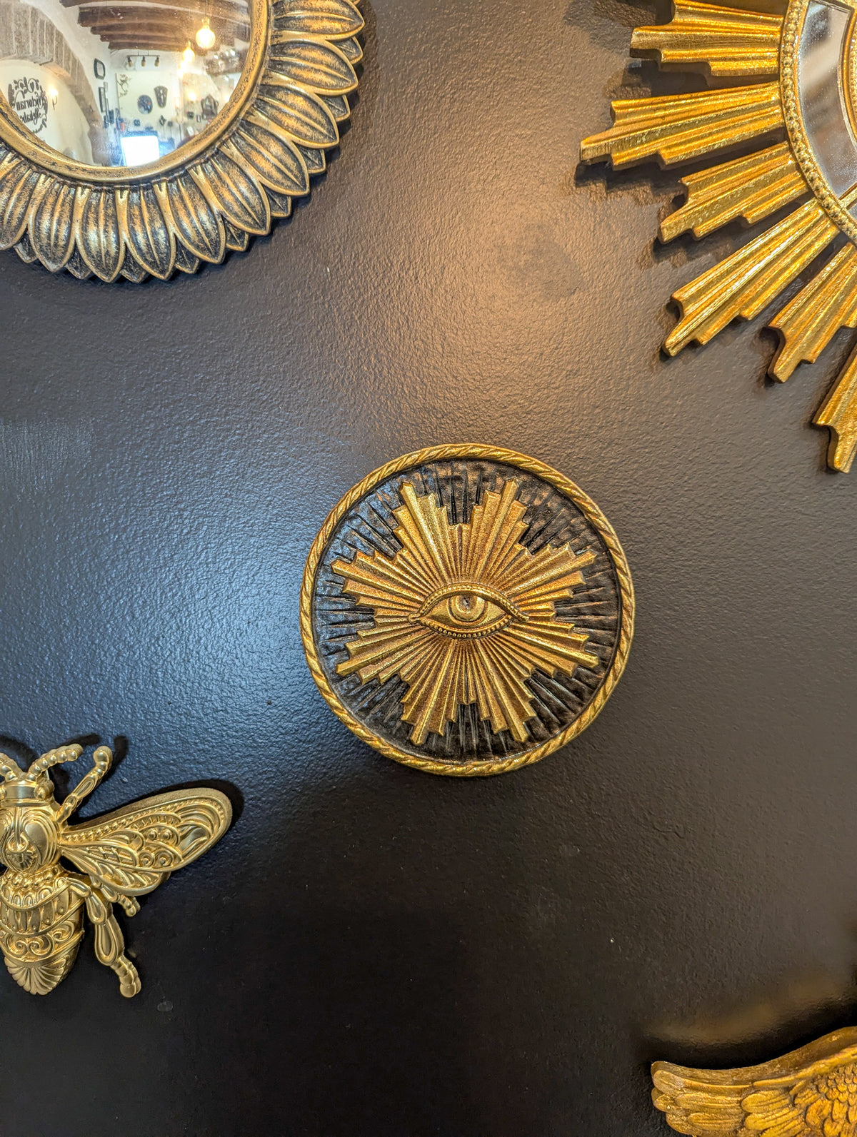 Soleil doré avec œil au centre sur mur noir, décoration ésotérique