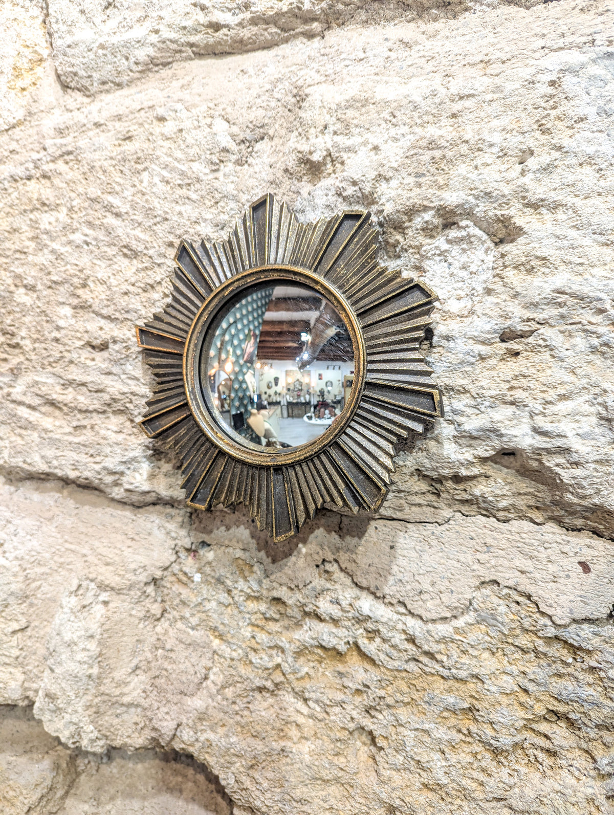 Miroir soleil sacré doré vieilli sur mur en pierre