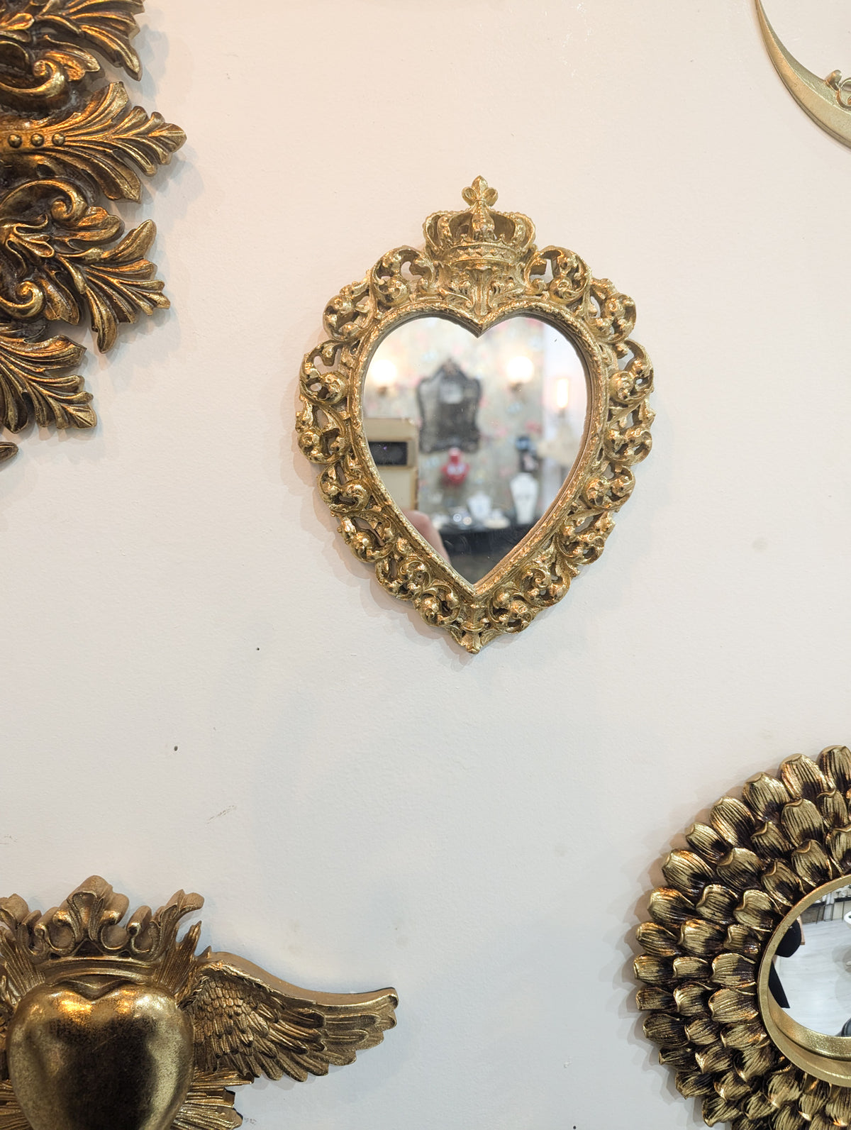 Miroir cœur sacré doré en accumulation murale avec d'autres miroirs ex-voto