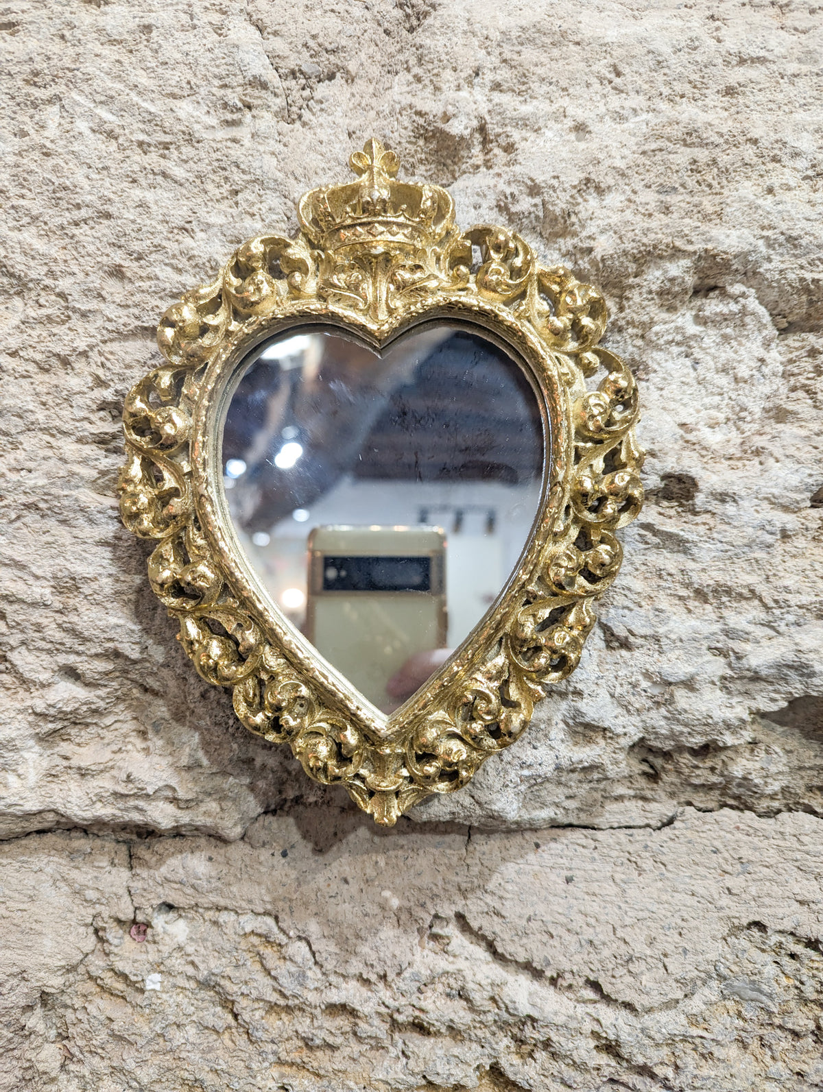 Miroir cœur sacré ex-voto accroché sur un mur en pierre
