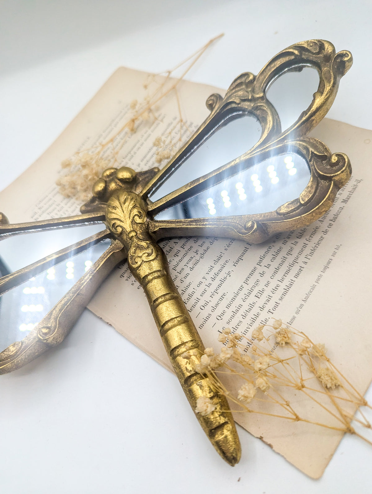 Miroir libellule doré vu de biais, détail du corps sculpté