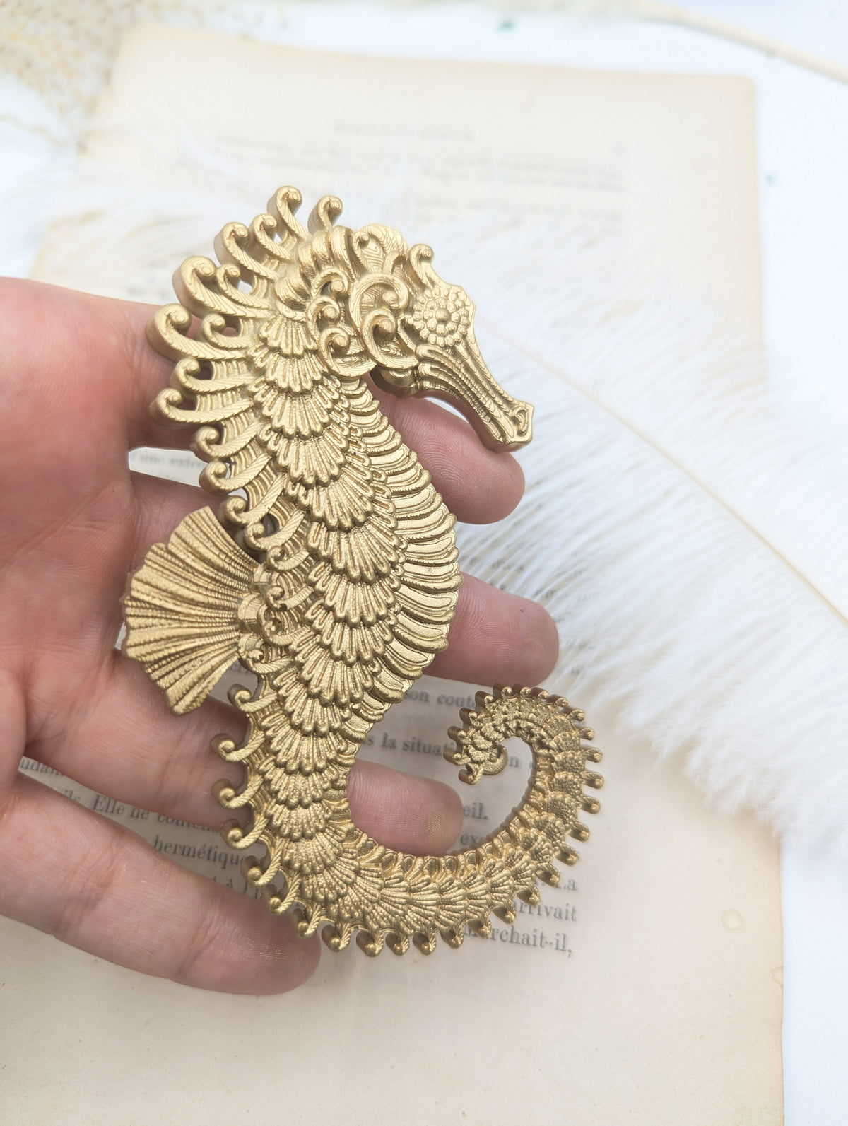 Hippocampe baroque en résine dorée tenu en main, 12 x 7 cm
