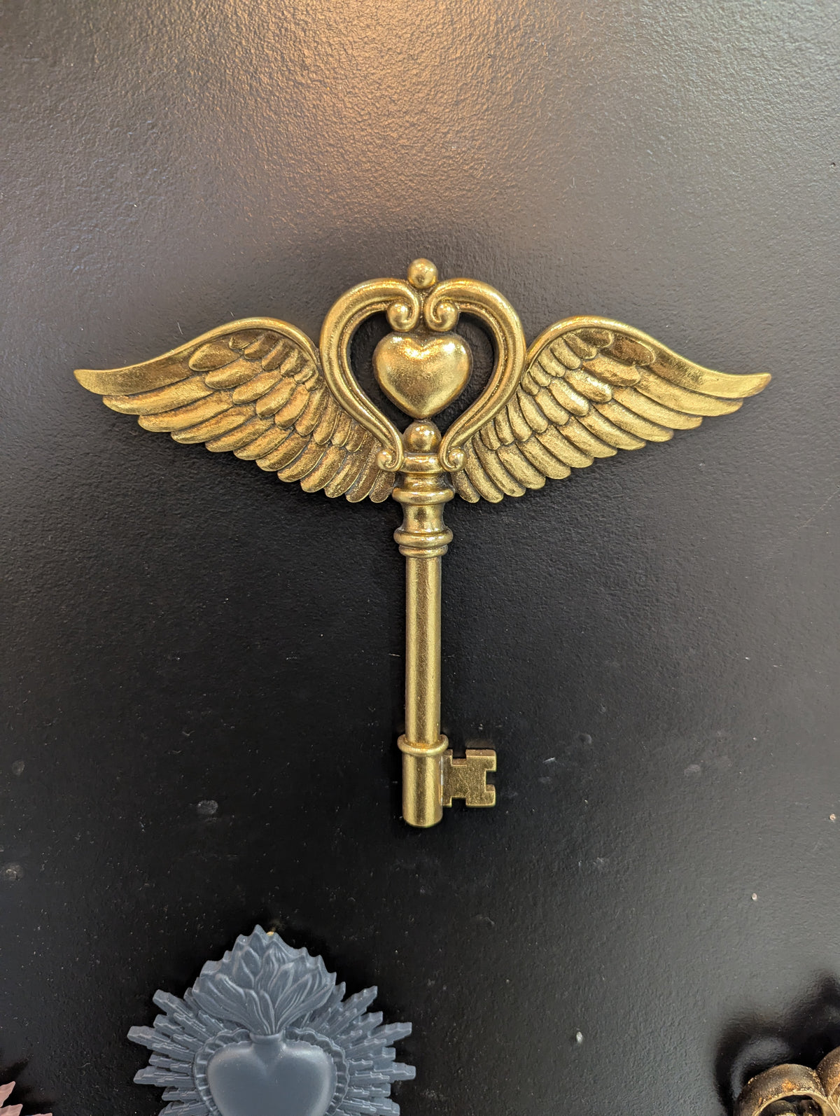 Clé de grimoire dorée à ailes d'ange sur fond noir