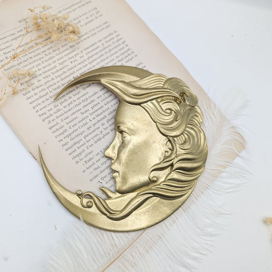 Lune dorée avec visage féminin posée sur un livre ancien
