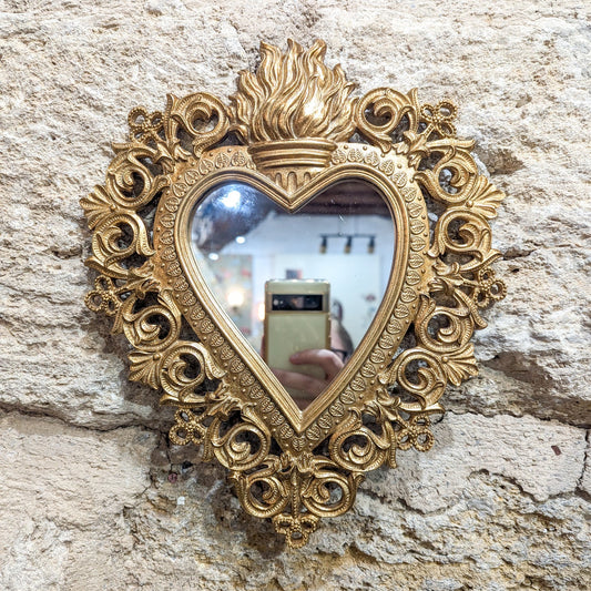 Miroir cœur sacré ex-voto doré accroché sur un mur en pierre